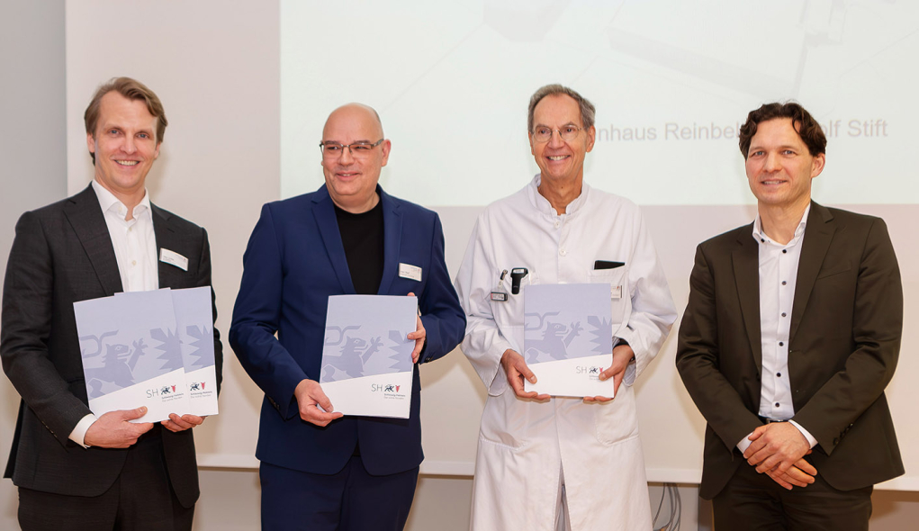 Das Krankenhausdirektorium hält die 4 Förderbescheide, die Gesundheits-Staatssekretär Dr. Oliver Grundei (r.) im Namen des Gesundheitsministeriums für die großen Bauprojekte des St. Adolf-Stiftes überreicht hat, stolz in den Händen: Krankenhaus-Geschäftsführer Fabian Linke (li.), Pflegedirektor Nils-Michael Wulf und der Ärztliche Direktor Prof. Stefan Jäckle.